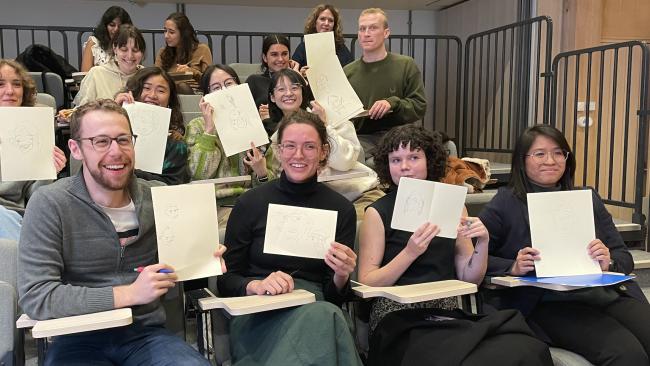 Workshop attendees smiling and holding up their drawings