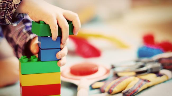 Image of A child's hands, building a tower of coloured blocks.
