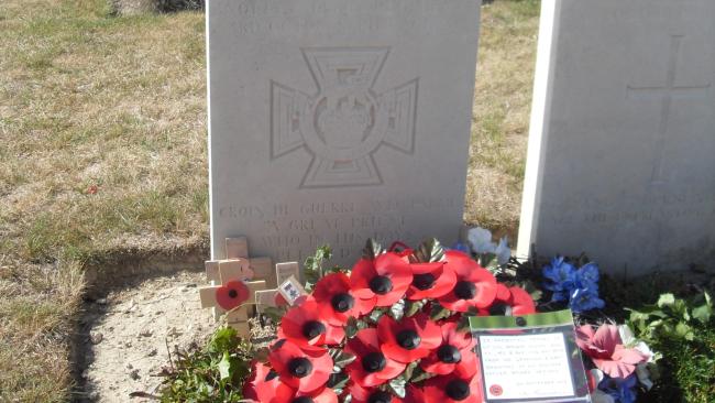 Image of War grave headstone with a poppy wreath laid in front of it