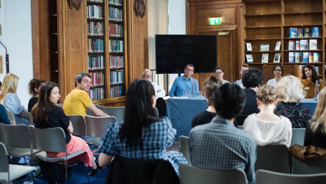 Image of A panel of speakers facing a room full of students in the Webb Library