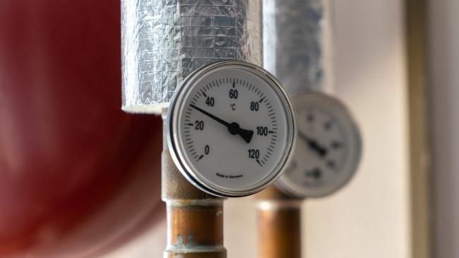 A picture of a thermometer attached to a copper pipe.