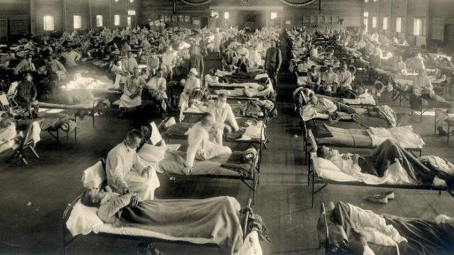 A historic mass hospital ward with patients being tended by medical staff