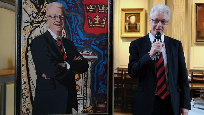 Professor Ian White speaking while standing next to his newly unveiled portrait