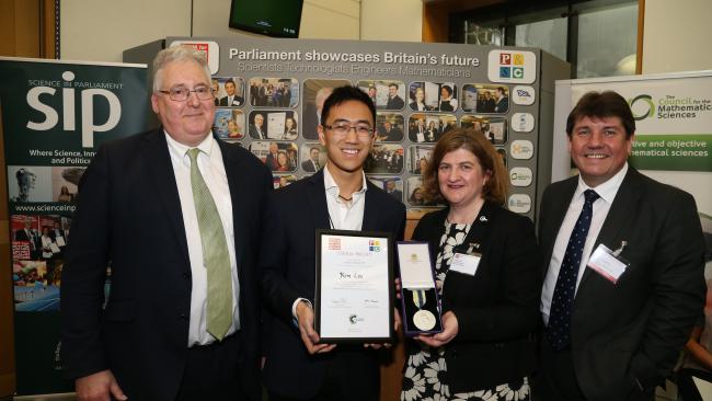 Group shot of four people, Kim Liu being presented with his certificate and medal