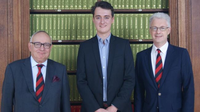Three men standing in front of library shelves