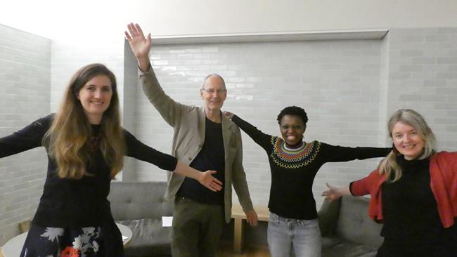 Four people posing with their arms in the air.