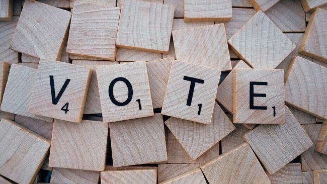 The word 'vote' spelled out using Scrabble tiles